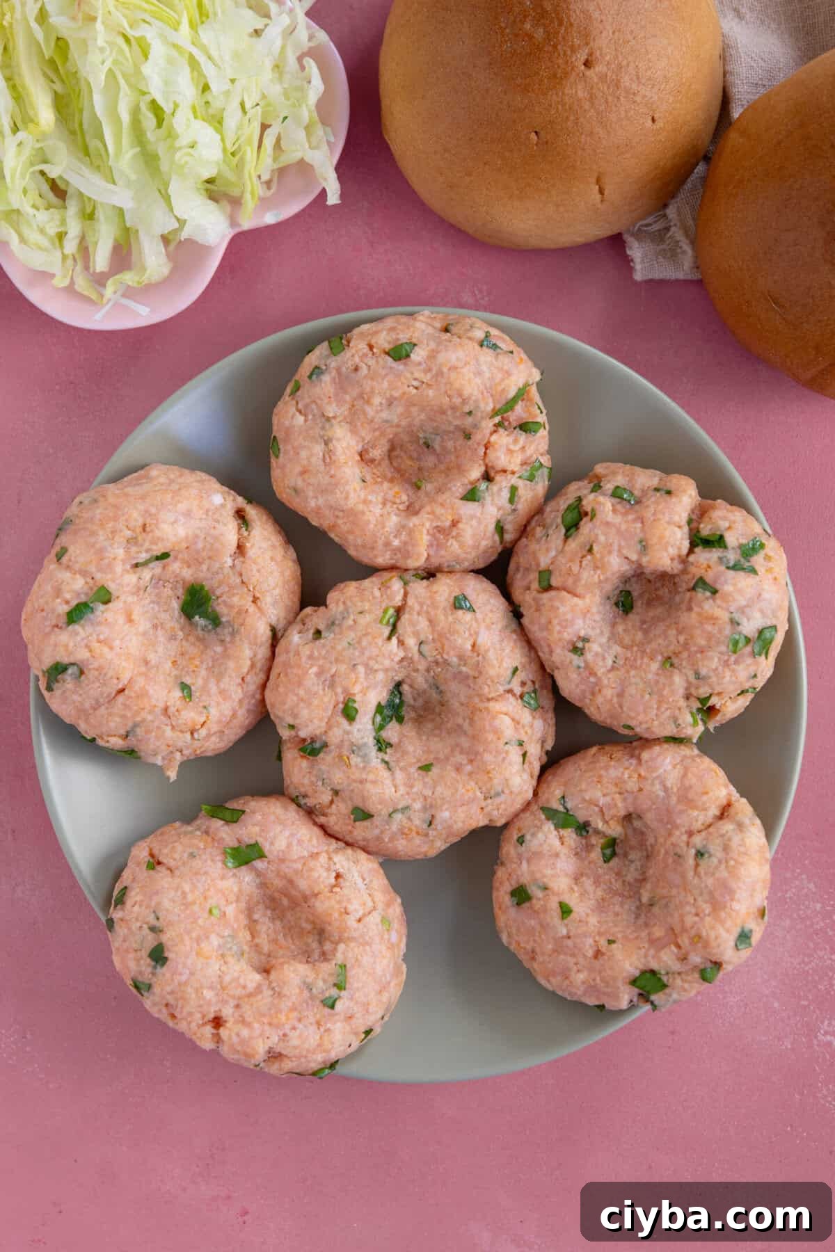 Process shot for chicken mince burgers showing the mixture formed into patties with a thumbprint in the centre.