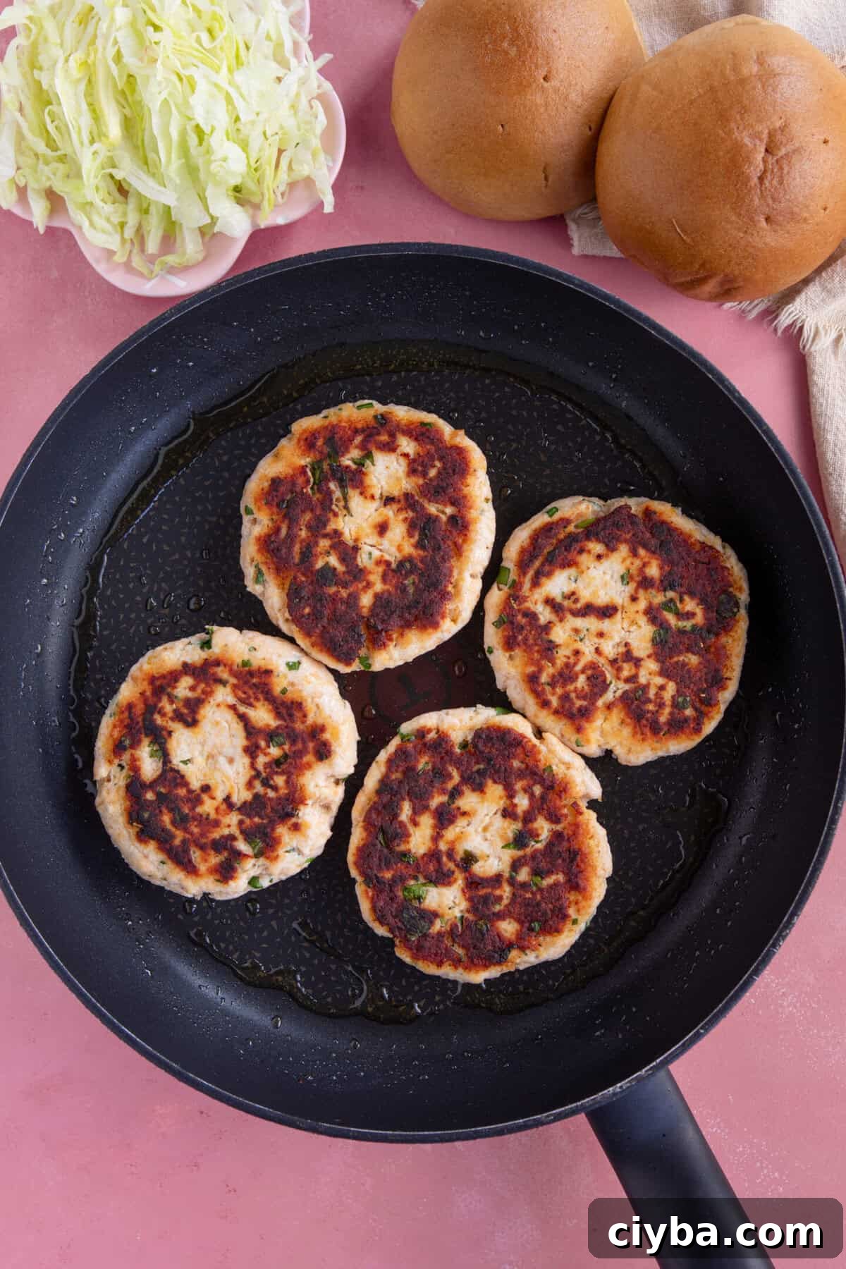 Process shot for chicken mince burgers showing the cooked chicken burger patties in a pan.