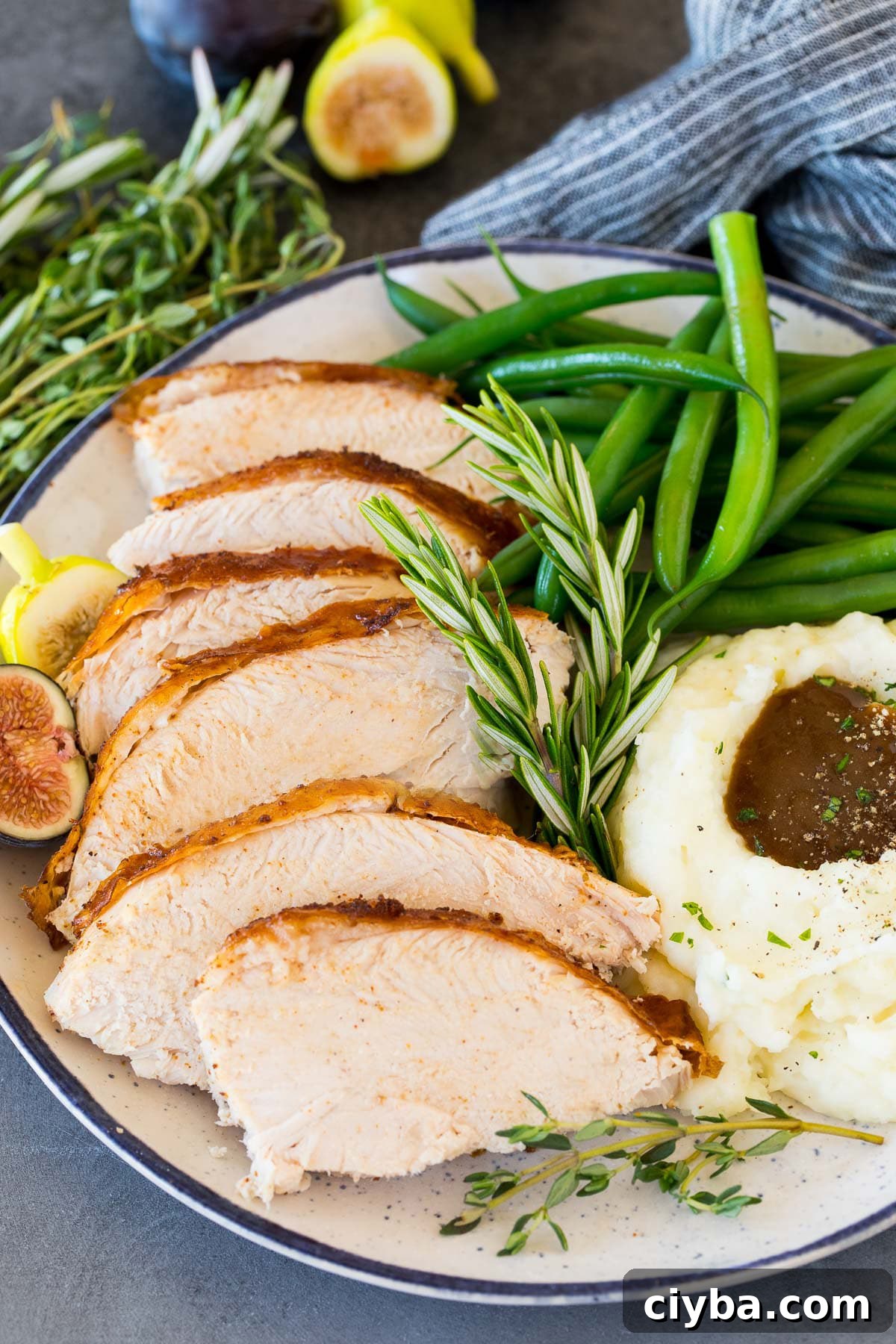 Sliced Cajun turkey on a plate with mashed potatoes and green beans.