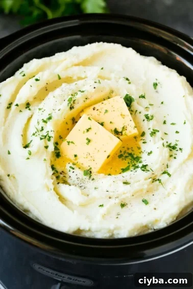Crock pot mashed potatoes topped with butter and parsley.