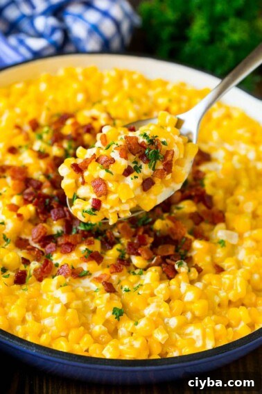 A spoonful of creamed corn topped with bacon and fresh herbs.