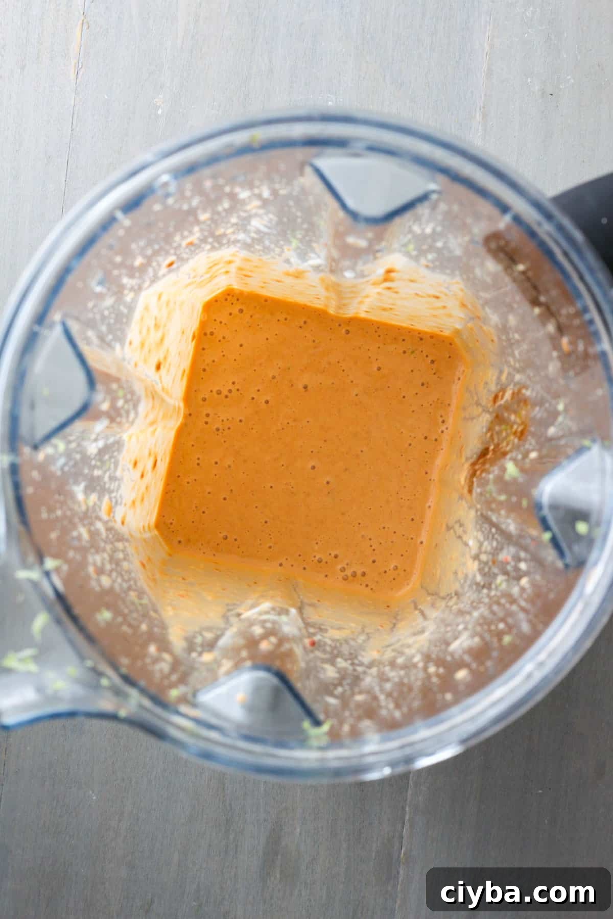 The inside of a blender with creamy chipotle lime sauce blended smooth.