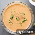 A glass bowl with creamy chipotle lime sauce topped with fresh scallions.