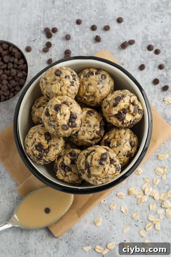 Tahini Chocolate Chip Bliss Balls served in bowl on top of parchment paper with chocolate chips and oats scattered and spoon of tahini 