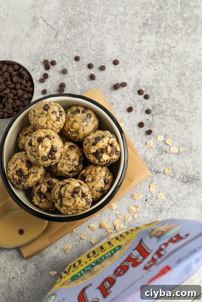 Tahini Chocolate Chip Bliss Balls served in bowl on top of parchment paper with chocolate chips and oats scattered and spoon of tahini 