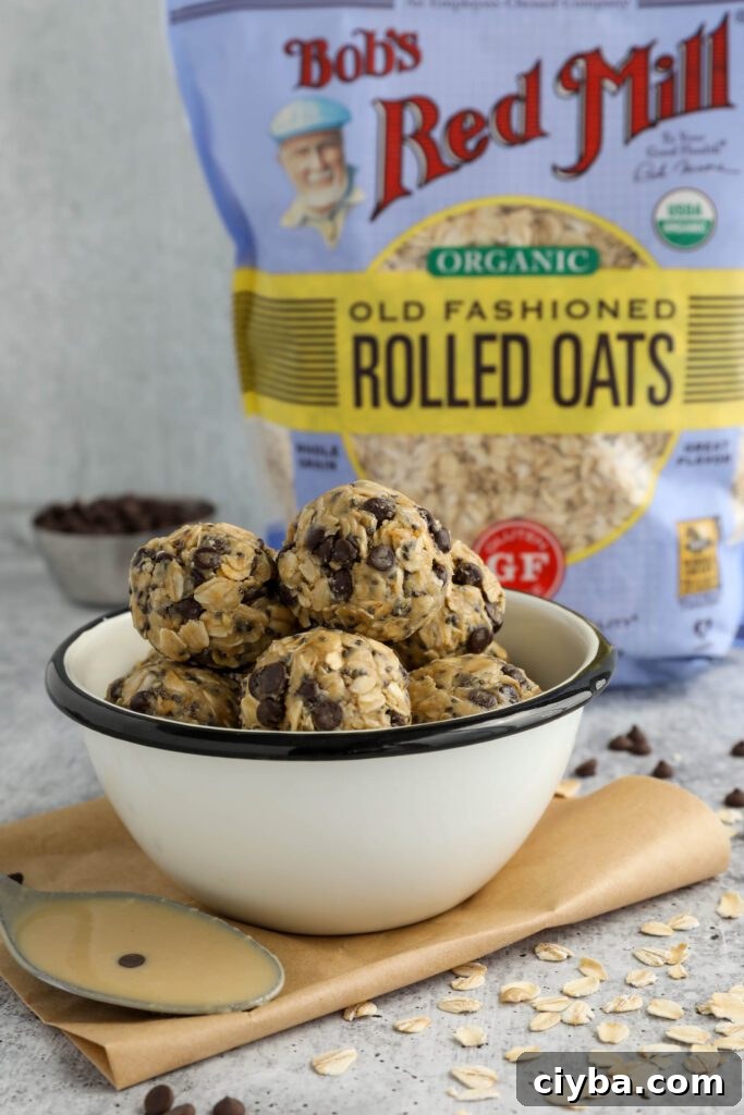 Tahini Chocolate Chip Bliss Balls served in bowl on top of parchment paper with chocolate chips and oats scattered and spoon of tahini 