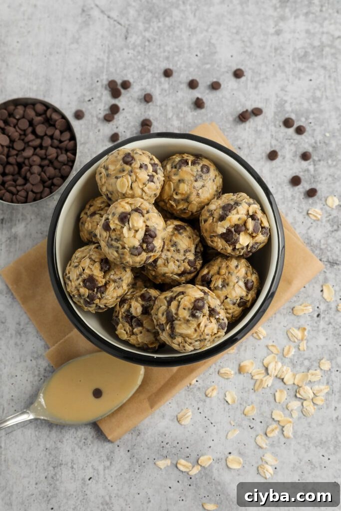 Tahini Chocolate Chip Bliss Balls served in bowl on top of parchment paper with chocolate chips and oats scattered and spoon of tahini 