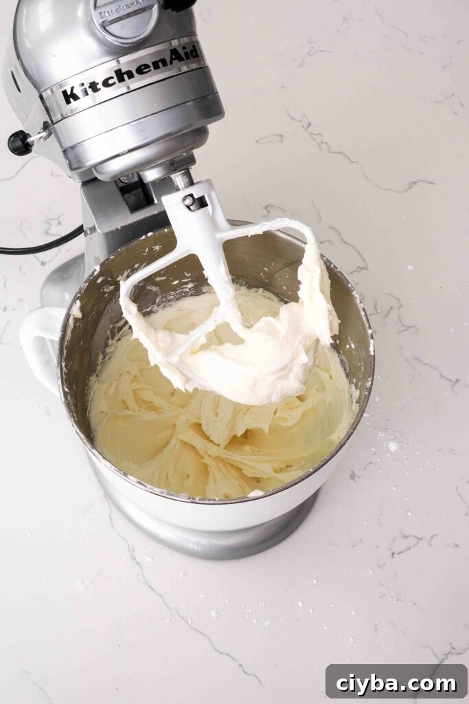 Red Velvet Cupcakes with Cream Cheese Frosting Recipe 12 A thick cream cheese frosting is clumped in the base of a beater attachment on a stand mixer.