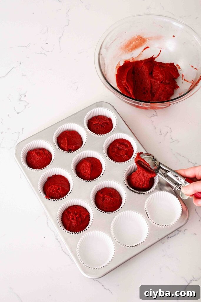 Red Velvet Cupcakes with Cream Cheese Frosting Recipe 7 A cookie scoop portions red velvet cake batter into paper cupcake liners.