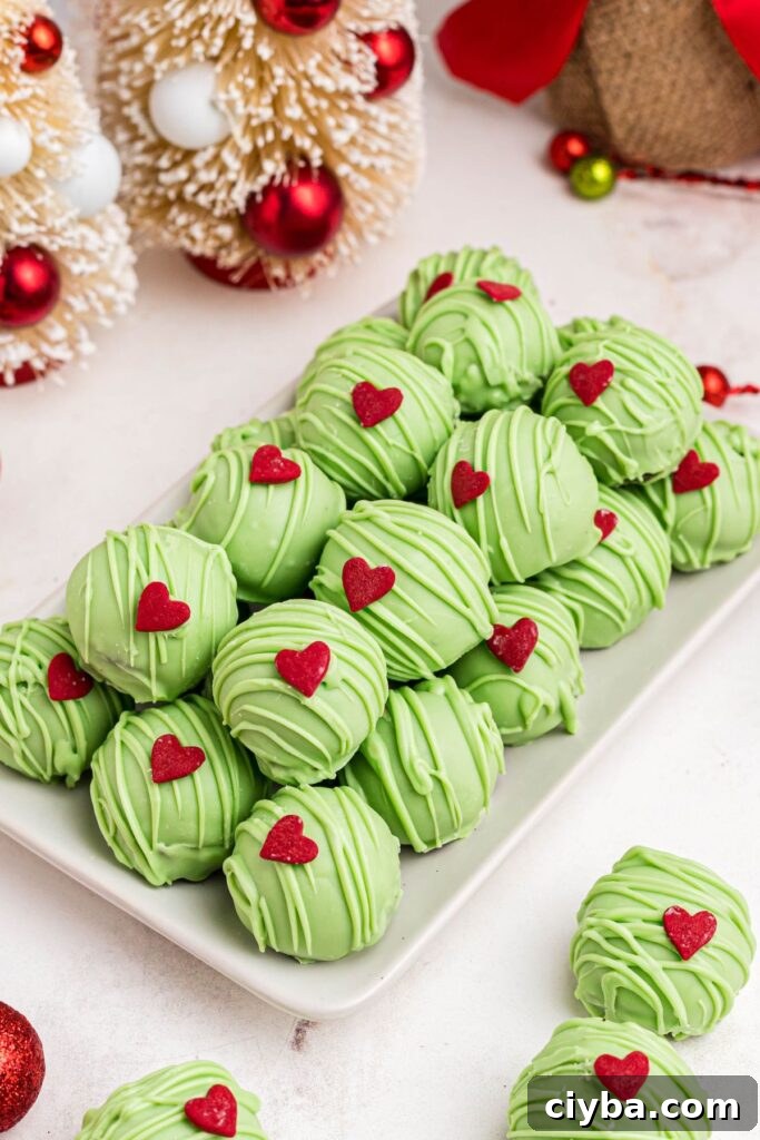 Green Grinch Oreo balls stacked on a white plate. 