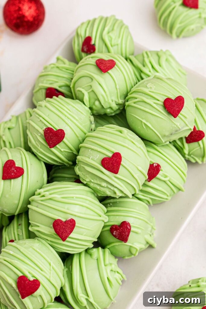 Grinch Oreo balls with a red sprinkle heart attached to the top. 