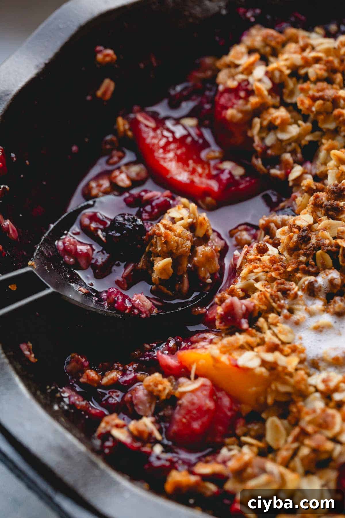 A spoon scooping up a portion of fruit crisp.