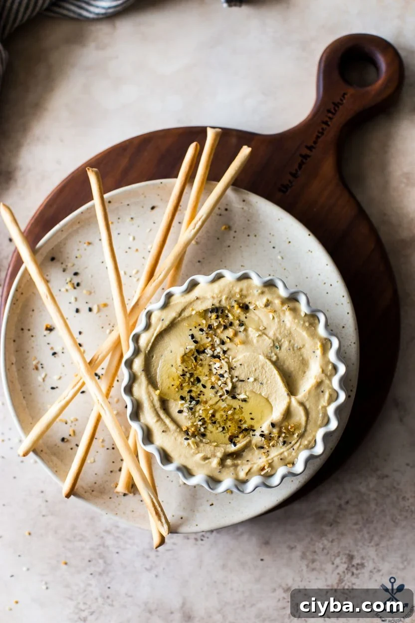Overhead photo of a small dish of hummus on a plate with breadsticks