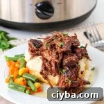 beef manhattan on a white plate with a side of cooked mixed vegetables