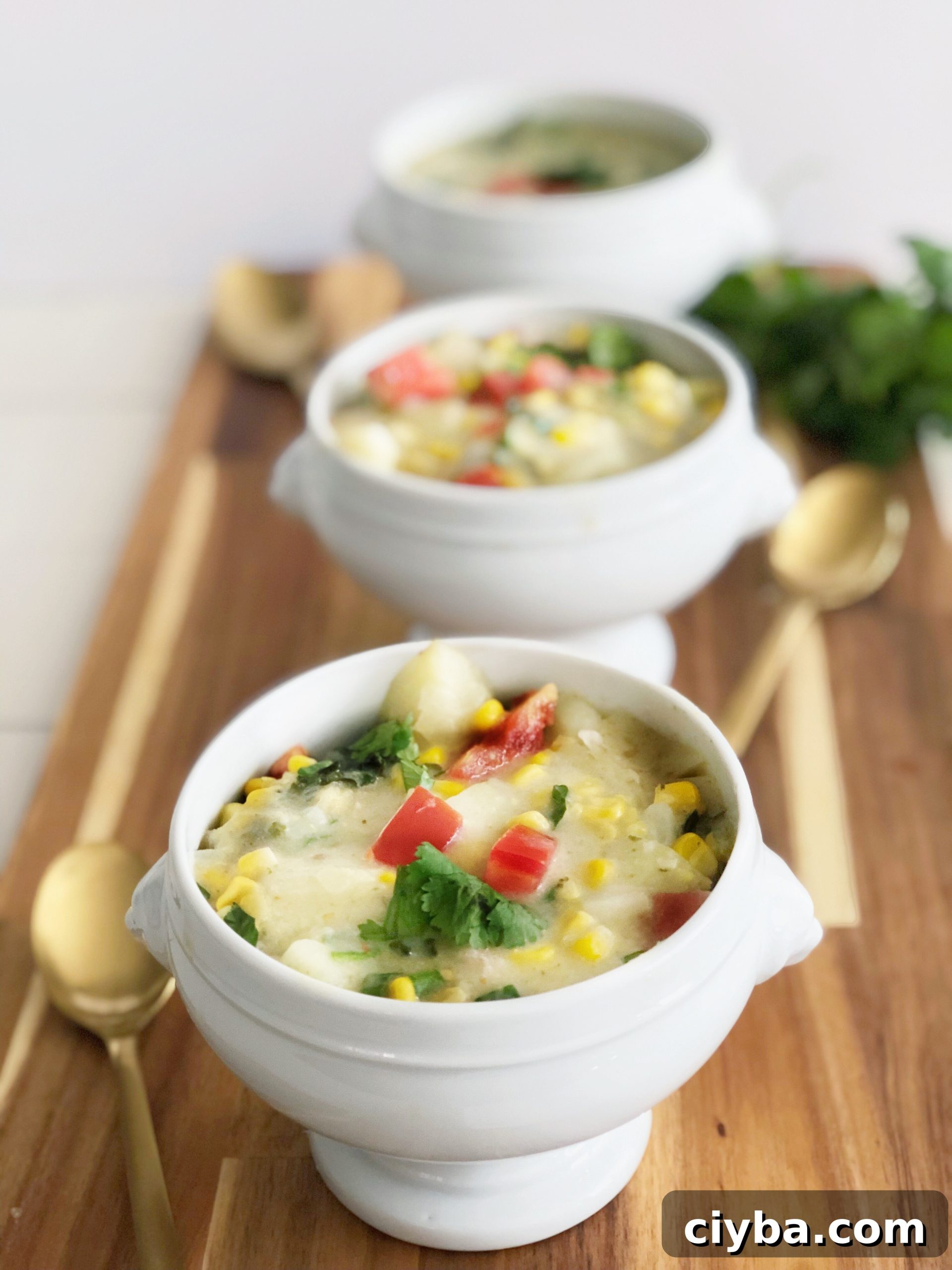 3 bowls of coconut corn chowder on a board