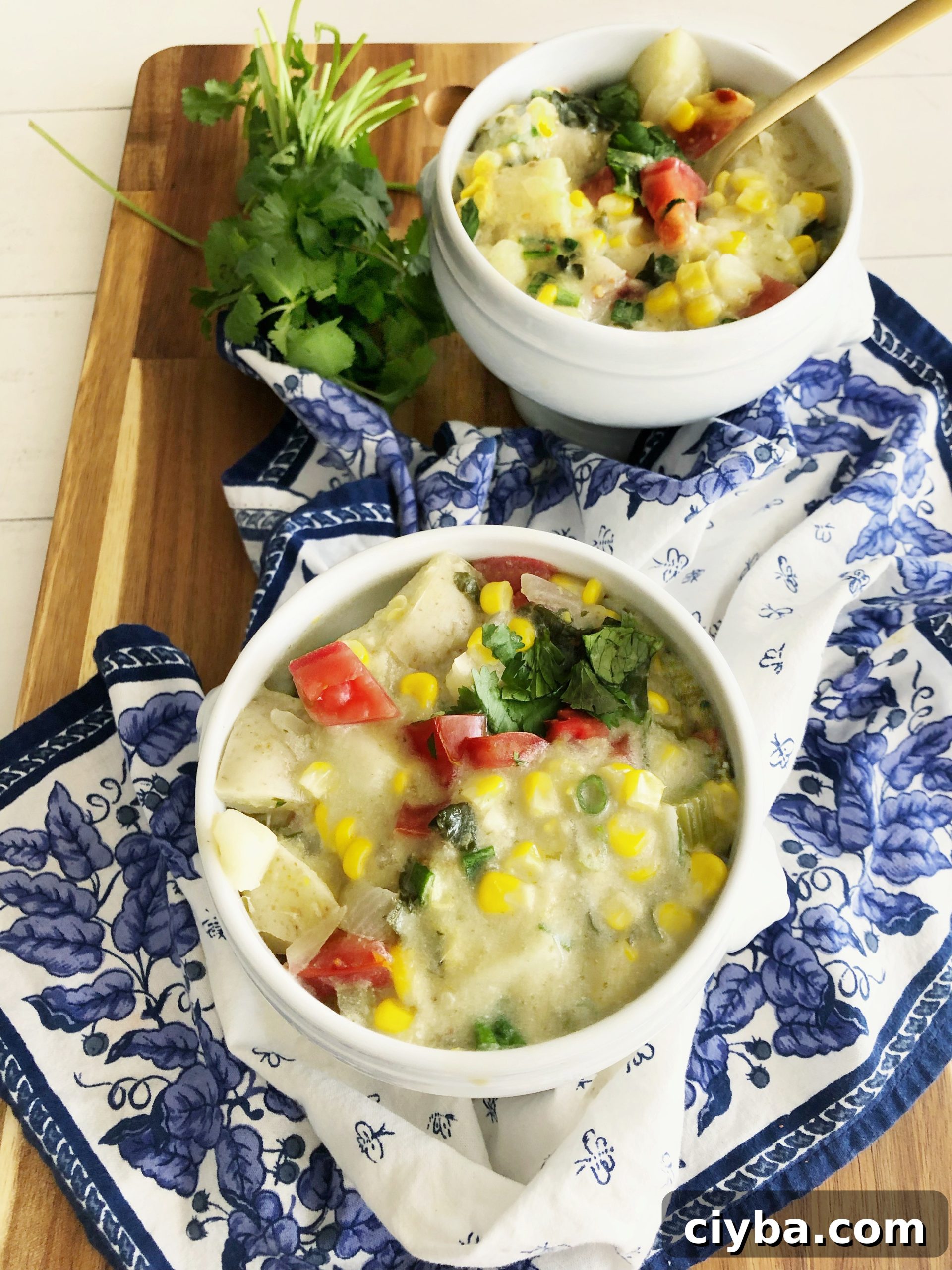 2 bowls of coconut corn chowder on a blue and white napkin and cutting board