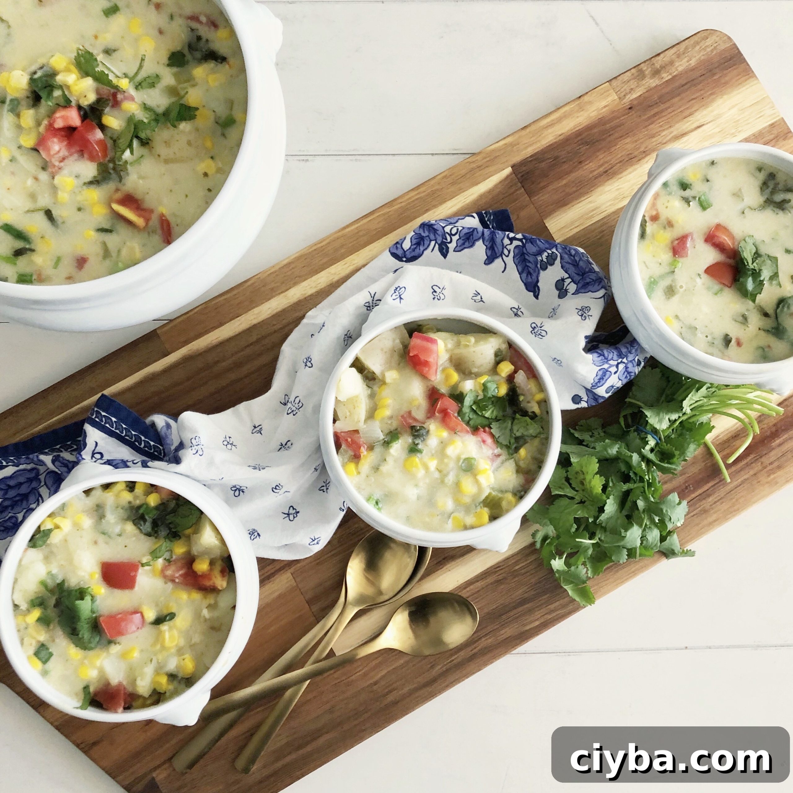 3 bowls of coconut corn chowder on a blue and white napkin and cutting board
