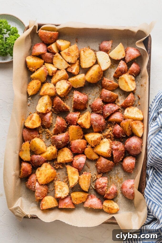 Crispy Parmesan-Crusted Red Potatoes for Dinner 6 Seasoned baby red potatoes spread out on a parchment-lined baking sheet, ready to roast.