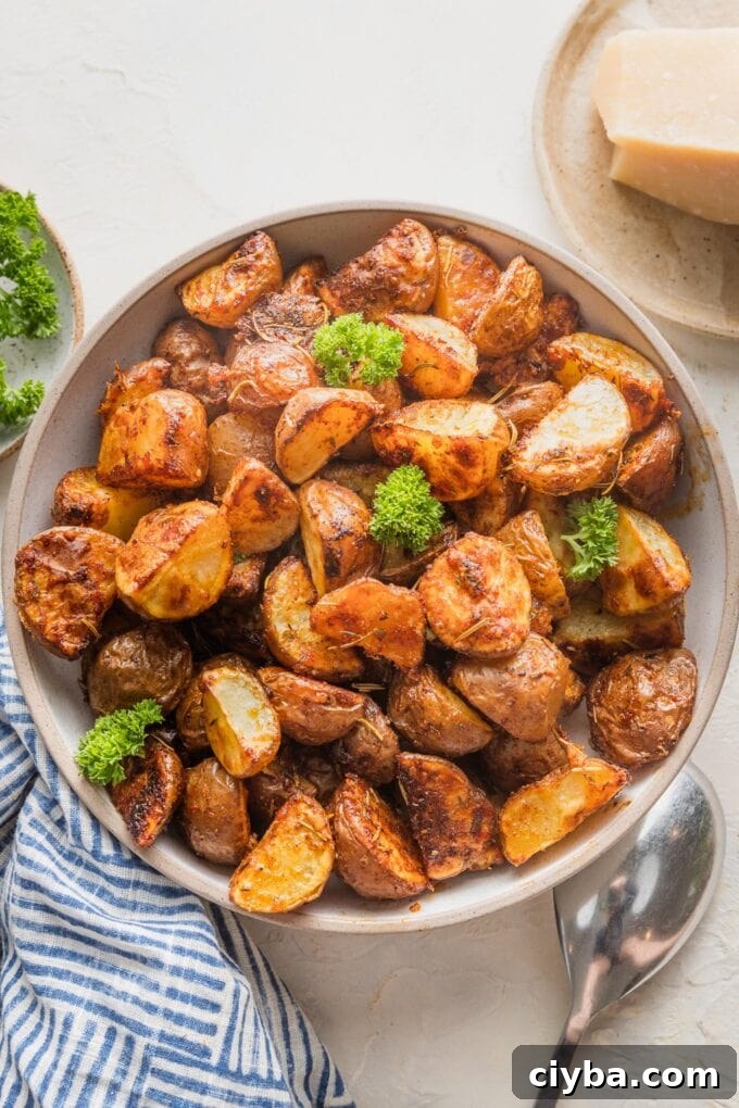 Crispy Parmesan-Crusted Red Potatoes for Dinner 8 Small serving bowl filled with a side dish of Parmesan crusted roasted red potatoes garnished with leaves of curly Italian parsley.