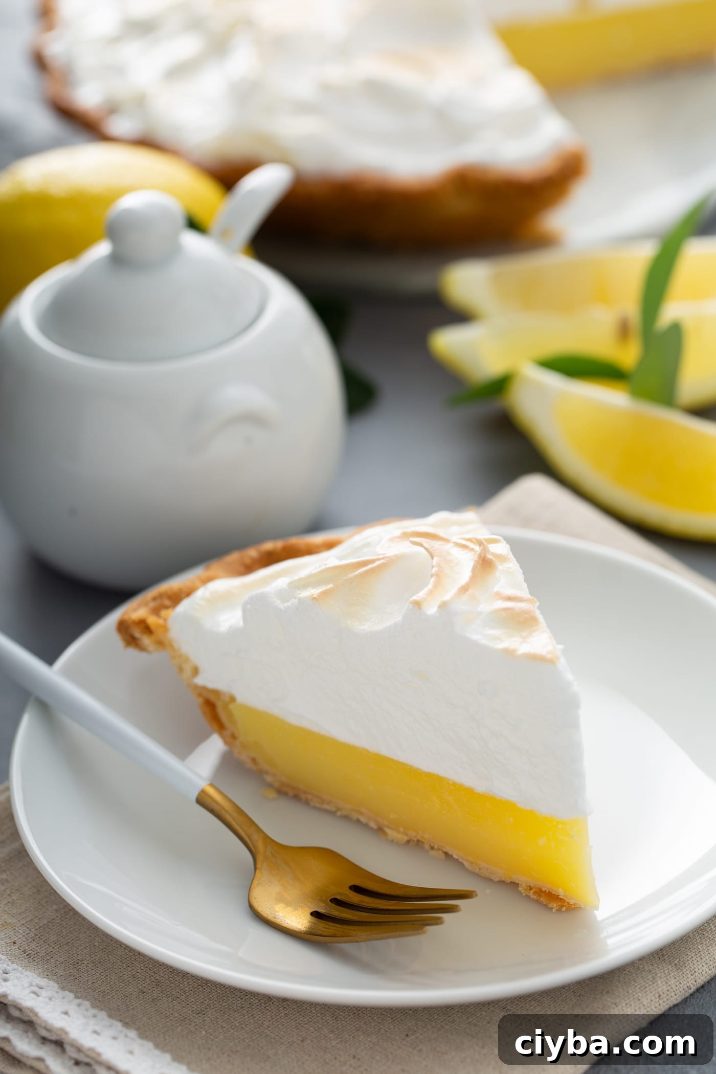 A slice of lemon meringue pie with lemon wedges