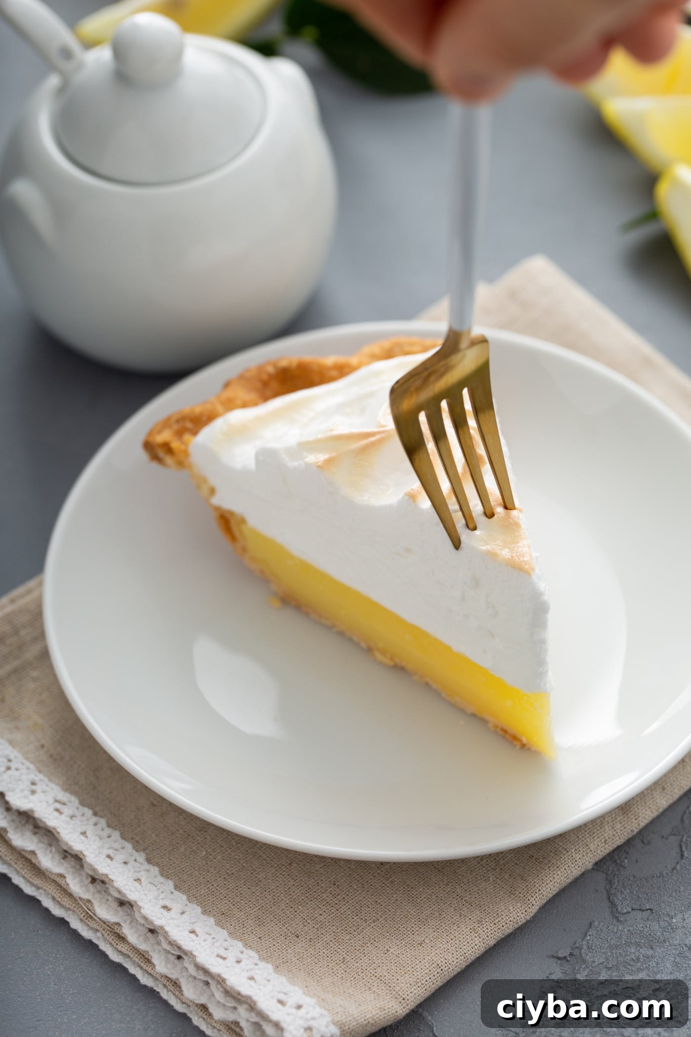 Fork poised at the tip of a slice of lemon meringue pie