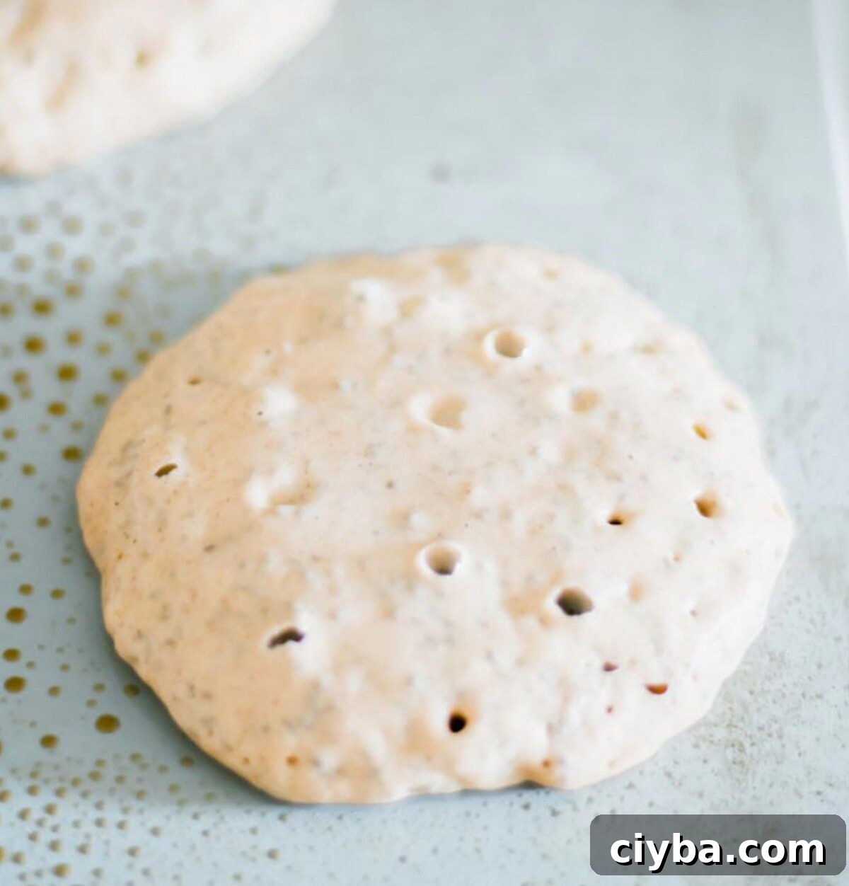 Pancake batter with small bubbles in it cooking on a nonstick pancake griddle.