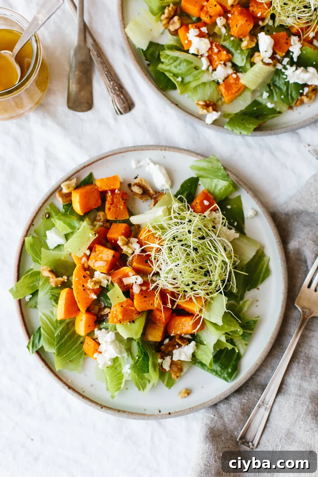 This roasted butternut squash salad is easy and comes together fast! There's just a handful of ingredients including roasted butternut squash, romaine lettuce, goat cheese, walnuts and sprouts but it's packed with flavor for a delicious fall salad recipe.
