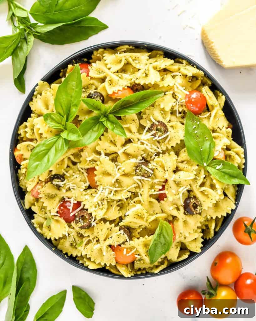 pesto pasta salad in a serving bowl with basil leaves on top.