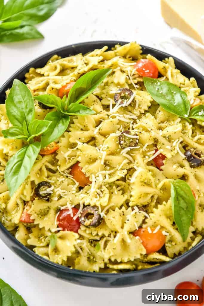 easy pesto pasta salad with fresh basil leaves on top.