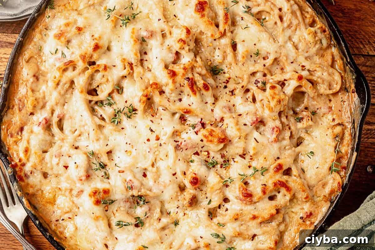 freshly baked spaghetti chicken in a skillet with golden brown melted cheese on top