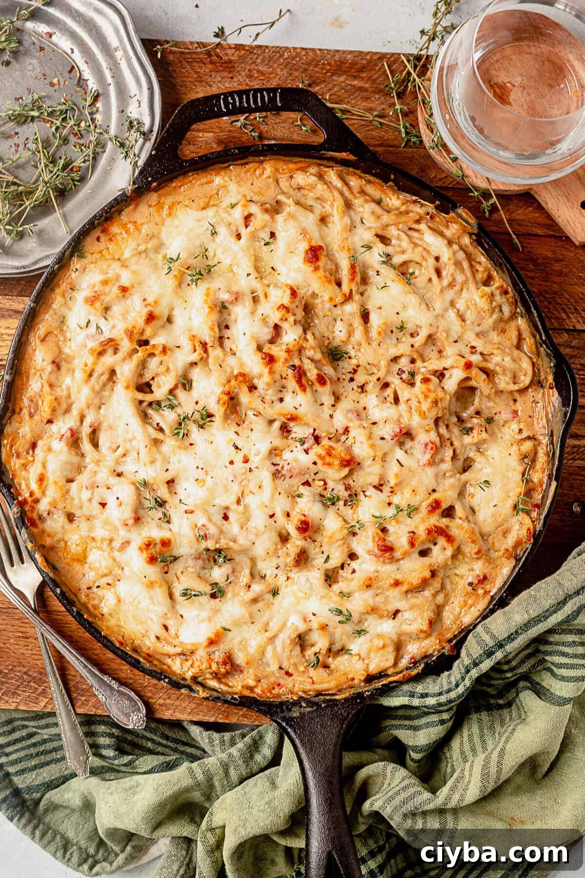 a skillet of spaghetti chicken covered in golden brown melted cheese