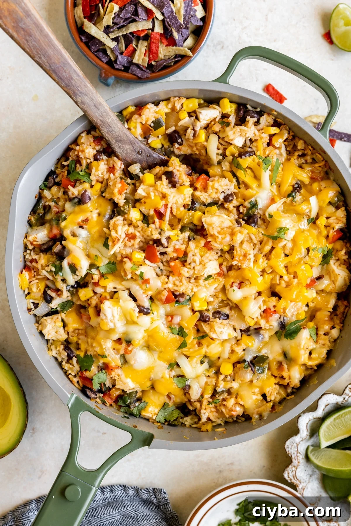 chicken, rice, beans and bell peppers in a skillet with cheese and cilantro on top.