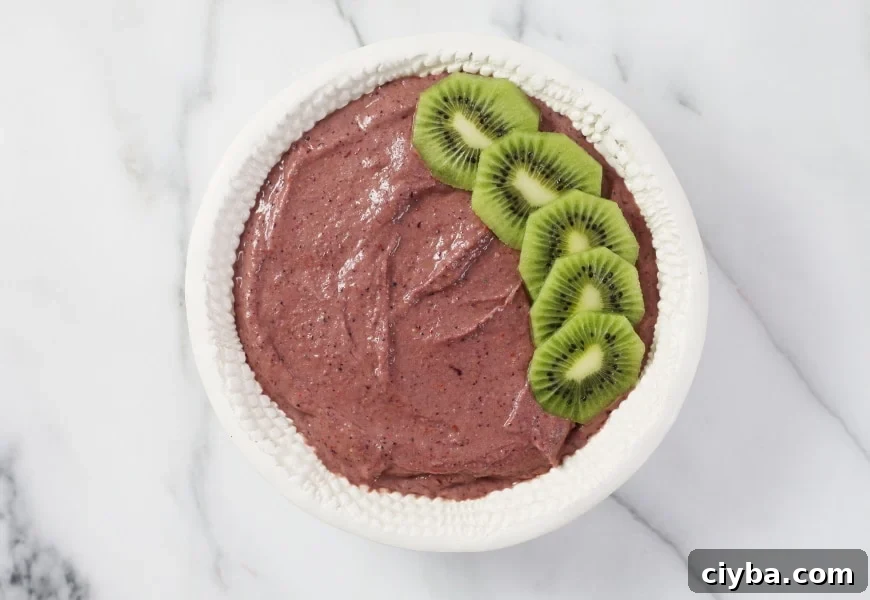 Process shot of adding fresh fruit to the top of the superfood berry smoothie bowl