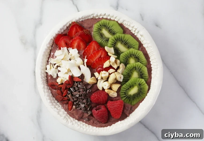 Superfood berry smoothie bowl topped with fresh fruit, cacao nibs, nuts and coconut