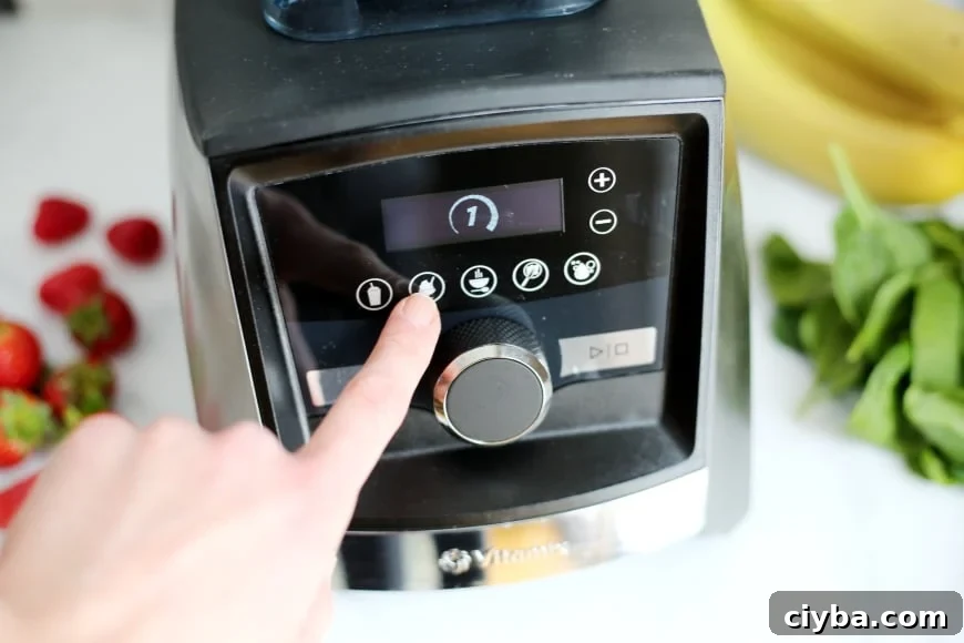 Finger pressing the "on" button on the Vitamix blender 