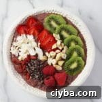 Superfood berry smoothie bowl topped with fresh fruit, cacao nibs, nuts and coconut