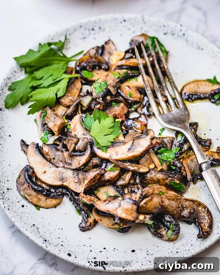 Sauteed mushrooms in white plate with sprig of parsley.