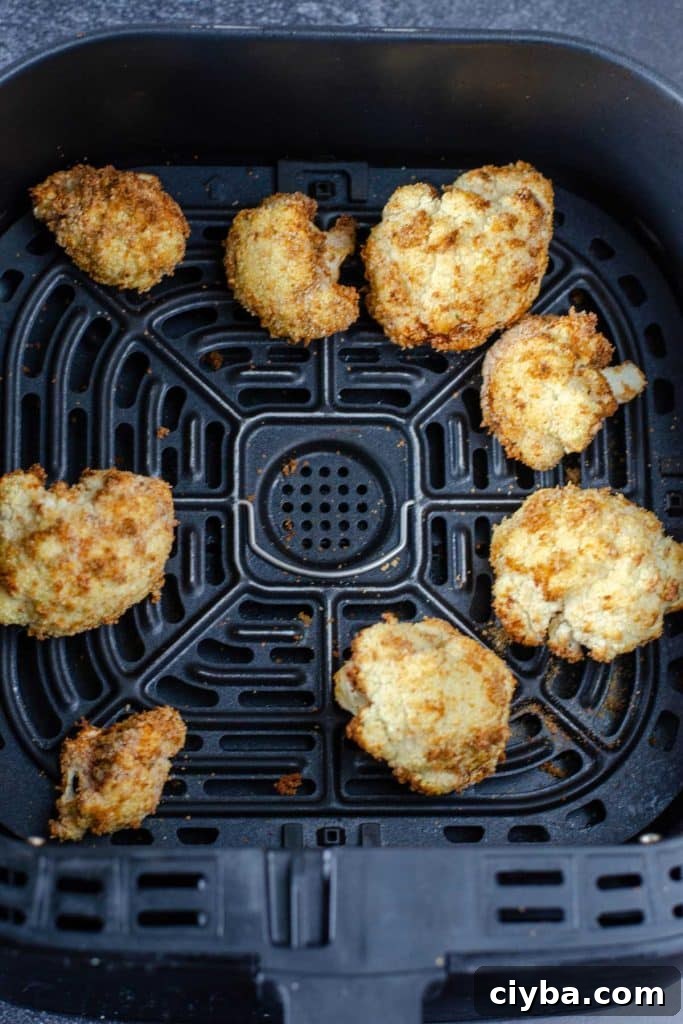 Golden brown cauliflower florets in an air fryer basket