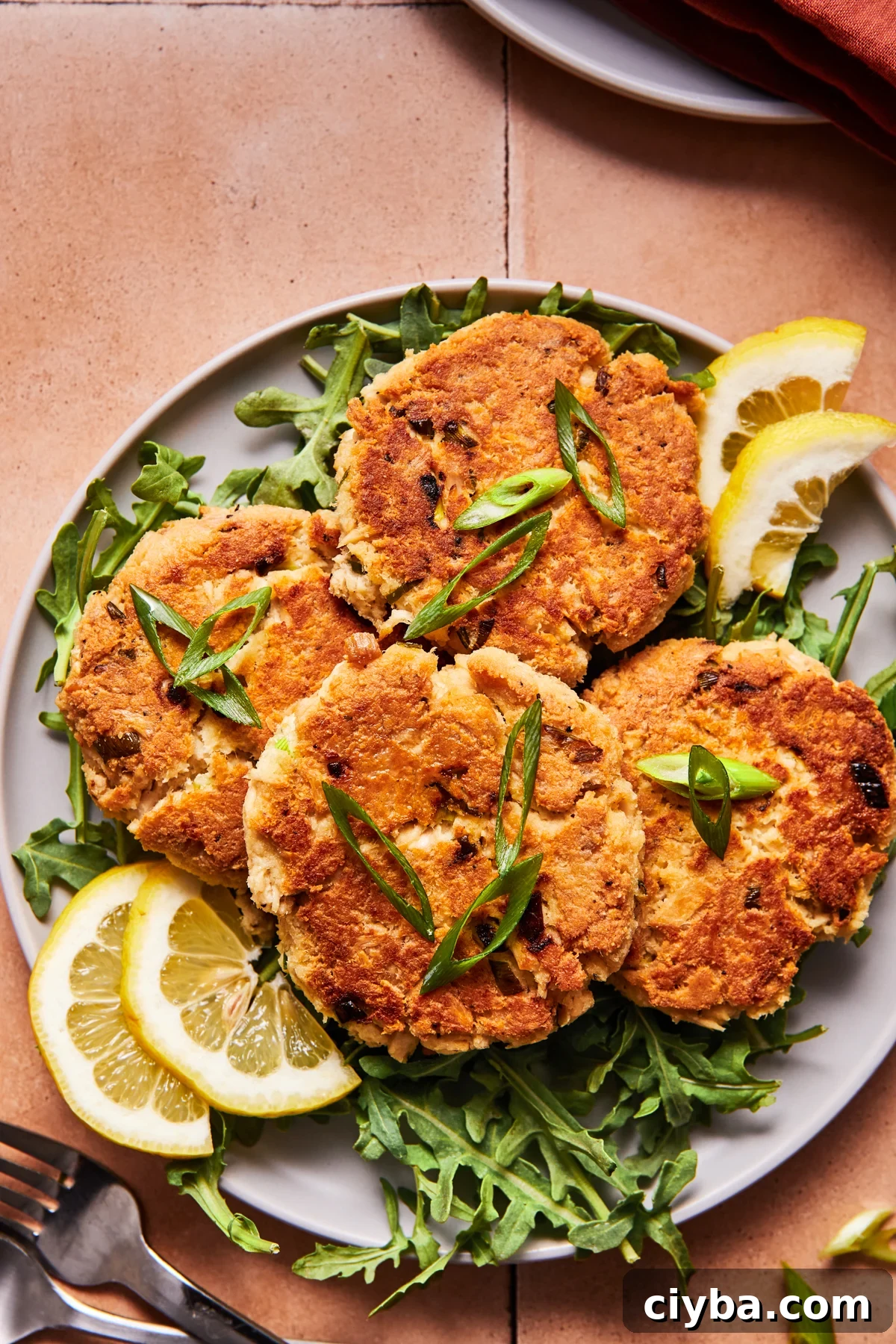 Four crispy tuna patties on a blue plate with herbs