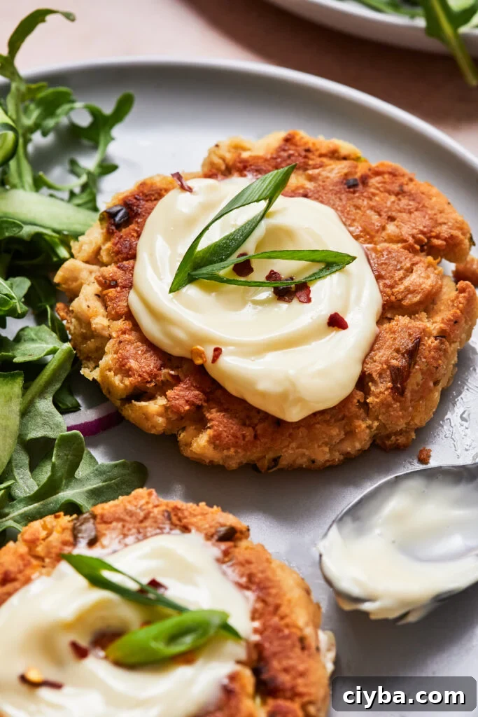 Cooked tuna patty on a salad with mayo, hot sauce, and greens