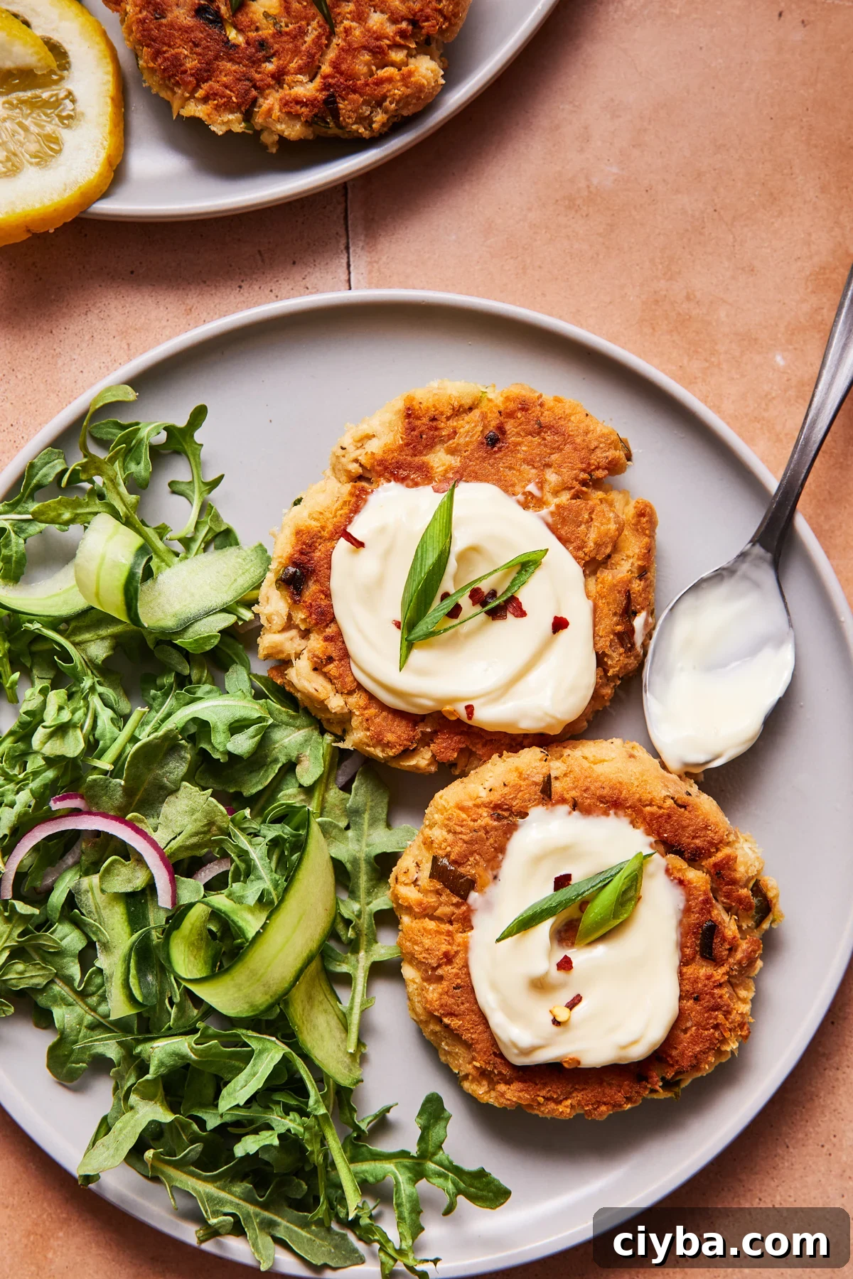 Cooked tuna patty on a salad with mayo, hot sauce, and greens