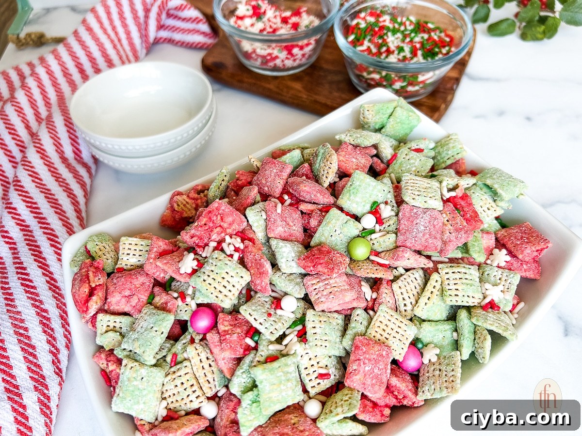 Large white dish containing Christmas muddy buddies next to smaller bowls filled with sprinkles on a white marble countertop.