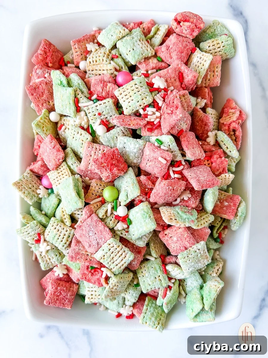 Sweet snack mix with red and green coated cereal in a white serving bowl.