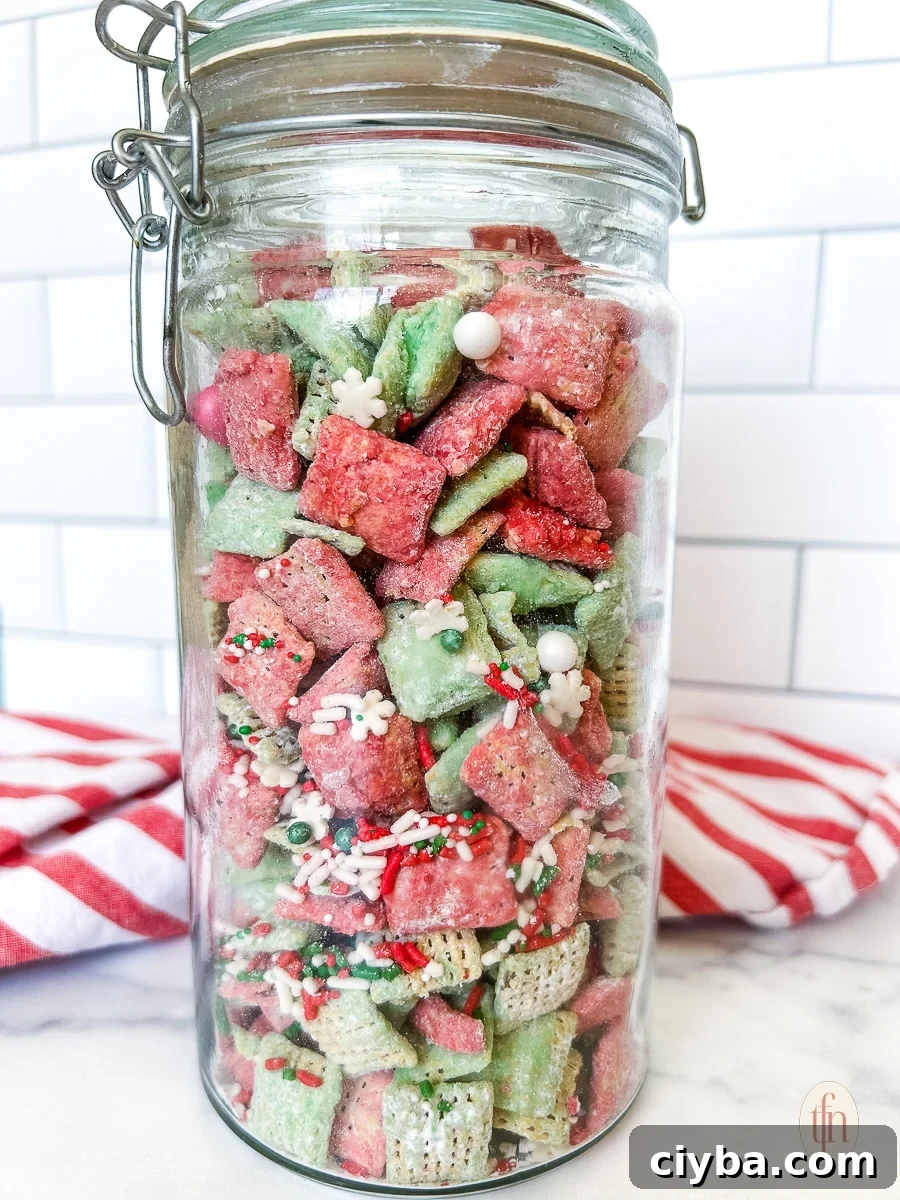 Christmas puppy chow in a tall glass canister on a marble countertop.