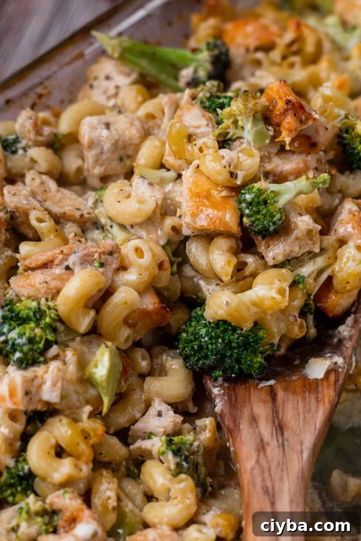 wooden spoon with pasta, broccoli and chicken on it