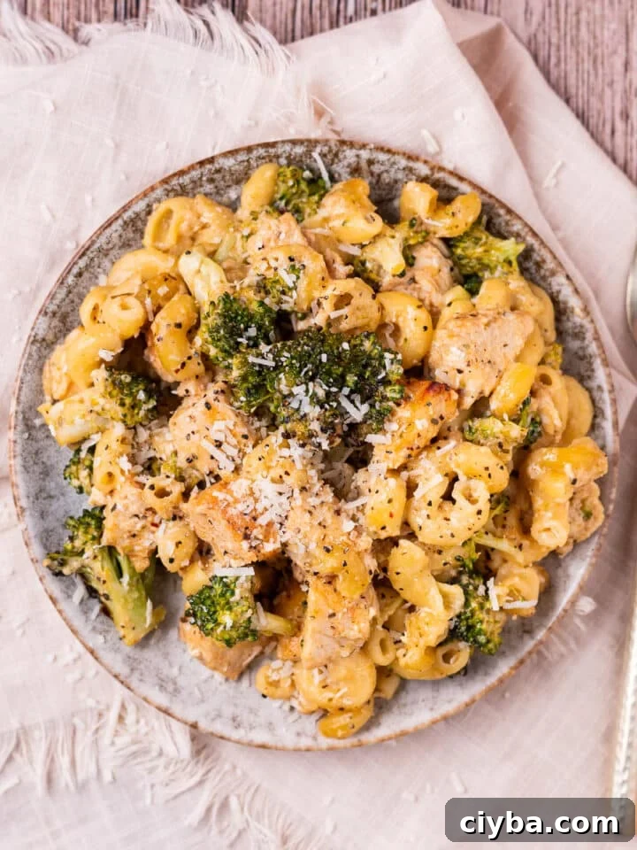 small plate with broccoli and chicken pasta topped with parmesan and black pepper
