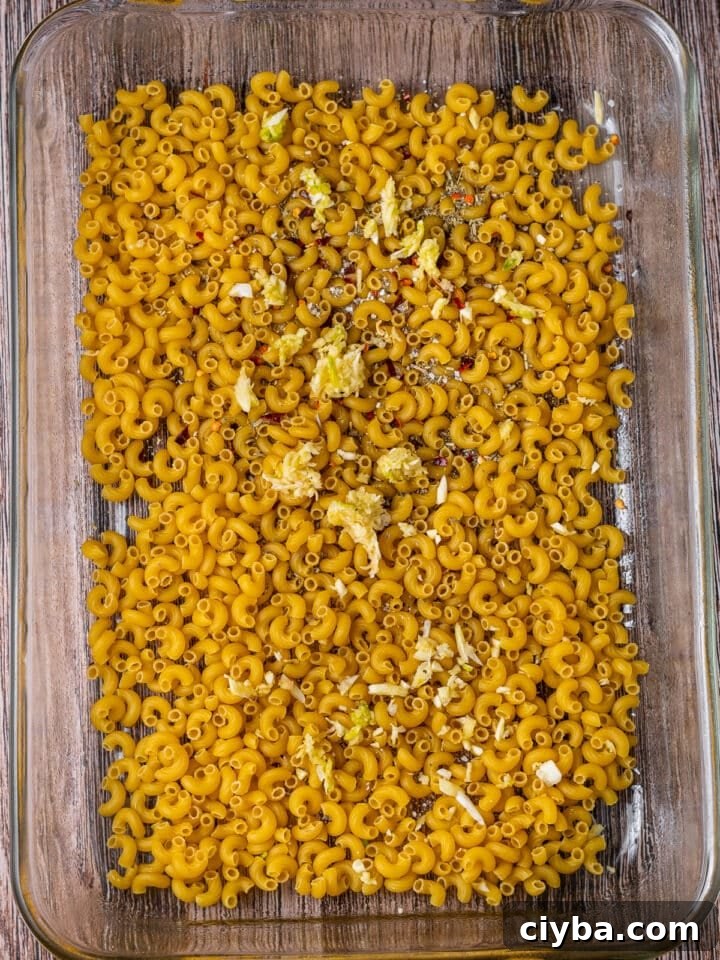 uncooked maraconi, seasonings and garlic in a baking dish