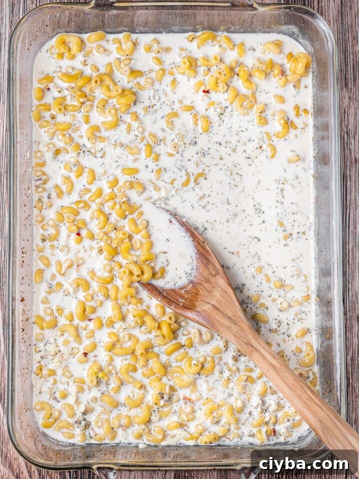 cooked macaroni being stirred with the milk and seasonings