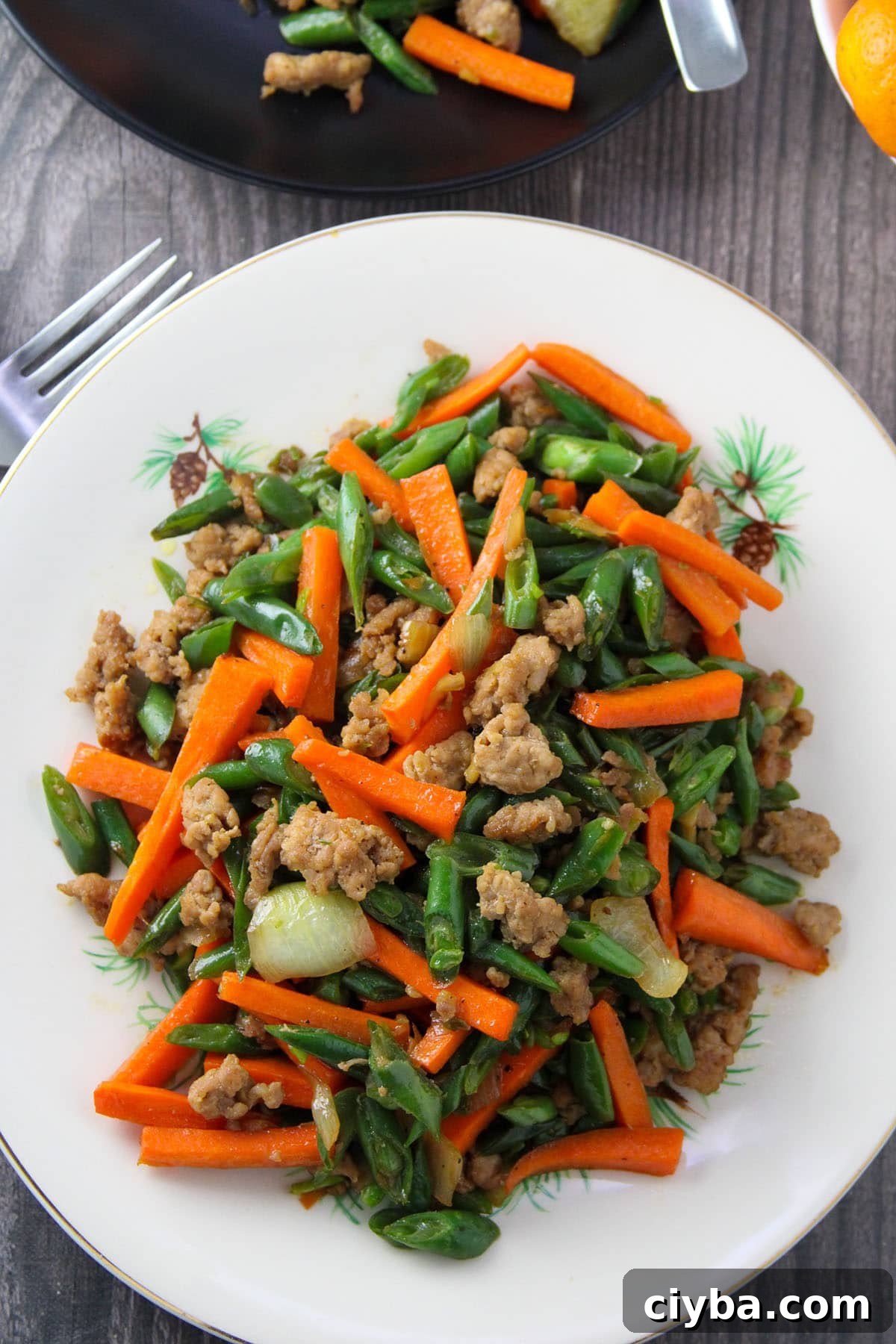 green bean stir-fry with carrots and minced pork on a white serving platter