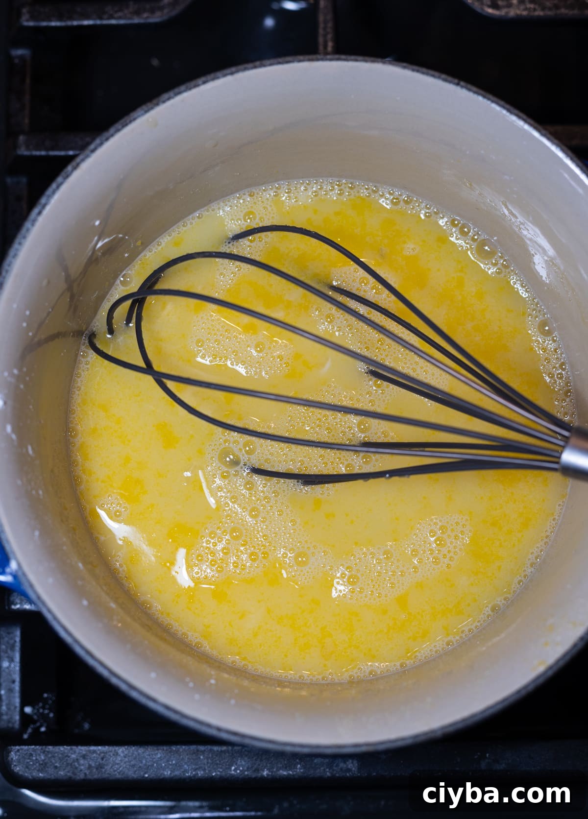 Person combining lemon pie filling in a saucepan.